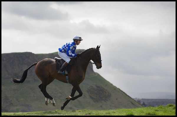 Jockey Robert Hogarth and Soul Magic gallop past Arthur's Seat as they prepare for the Edinburgh Cup 2014