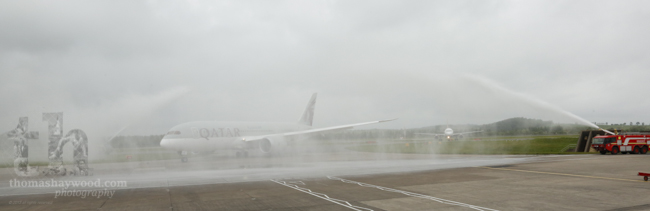 Qatar Airways Dreamliner slightly obscured by the spray