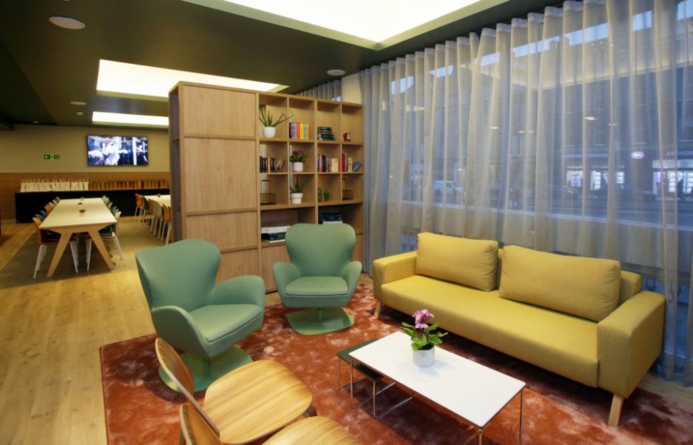 Dark green swivel chairs and wooden chairs, light green sofa, small table and a wooden bookshelf make up the new lounge